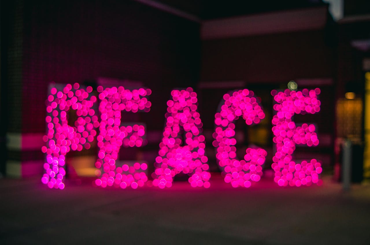 Blurred pink lights form the word PEACE in an artistic night scene.